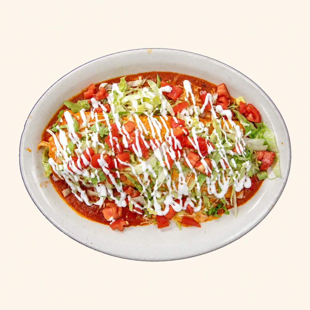 Burrito El Toreado topped with red sauce, lettuce, tomato and sour cream
