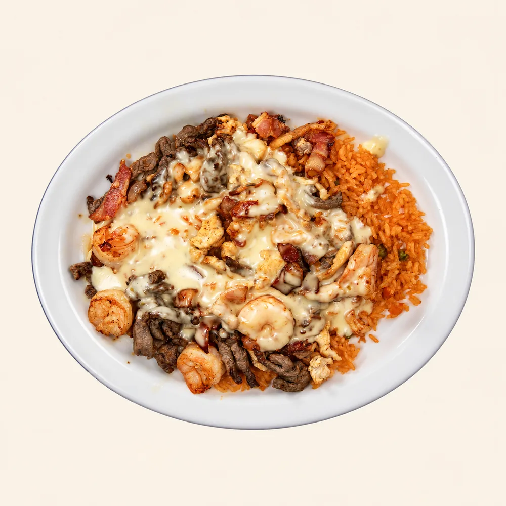 El Toreado house plate: grilled chicken, steak, shrimp and bacon over rice, covered in cheese dip