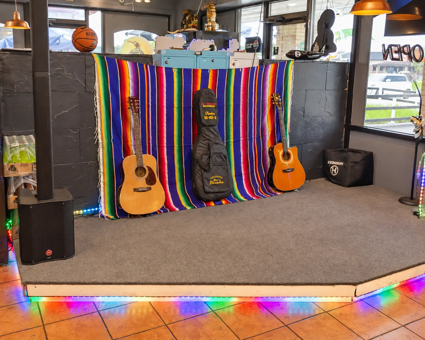The live-music stage at El Toreado with acoustic guitars, a striped serape backdrop and colored lights
